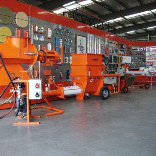 Maquinaria de construcción de color naranja junto a estanterías en interior de almacén