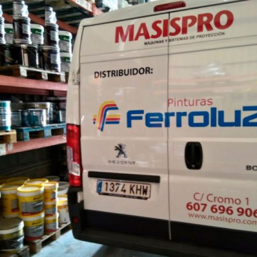 Interior del almacén con estantes y materiales a la izquierda y furgoneta en primer plano