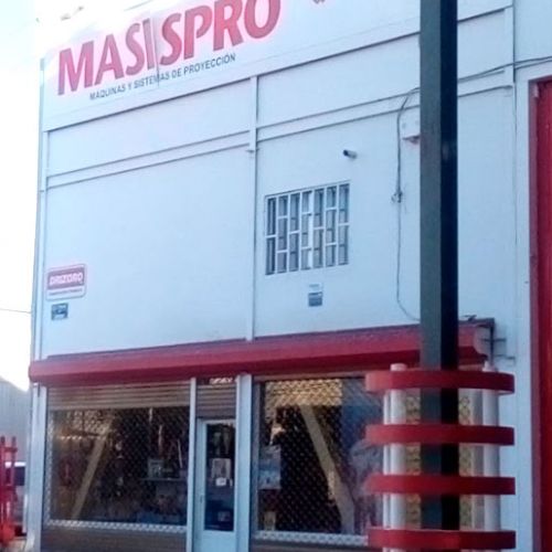 Imagen de exterior con logotipo rotulado en rojo sobre pared blanca