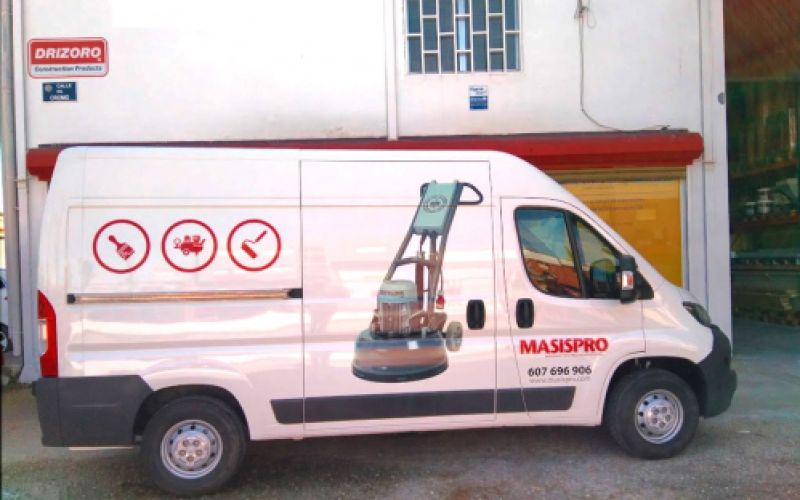 Vista lateral de la furgoneta rotulada en exterior de almacén