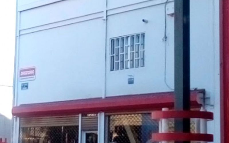 Imagen de exterior con logotipo rotulado en rojo sobre pared blanca