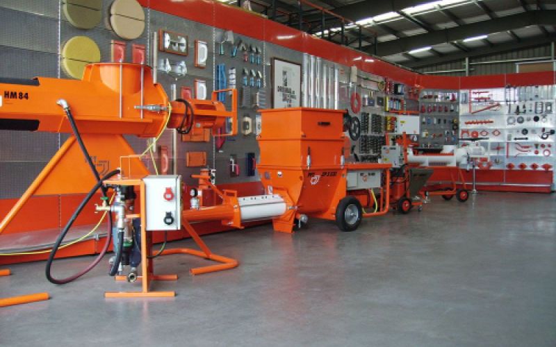 Maquinaria de construcción de color naranja junto a estanterías en interior de almacén