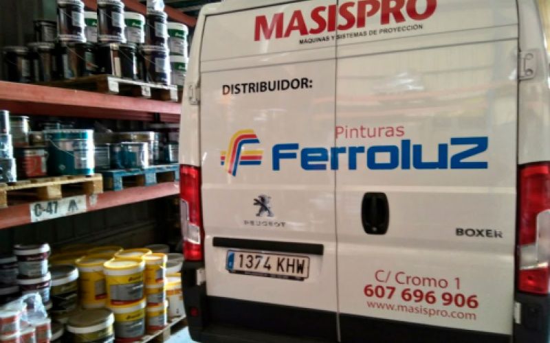 Interior del almacén con estantes y materiales a la izquierda y furgoneta en primer plano